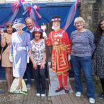 Smiling Guideposts members with cut outs of the Queen.