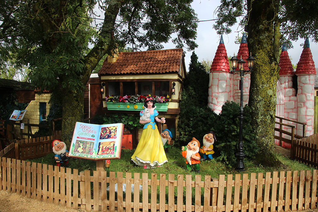 A Disney Snow White in front of model houses.