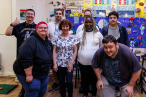 Smiling young members of Henry Smith House pose with their thumbs up. They are attending a mental health group for young people.