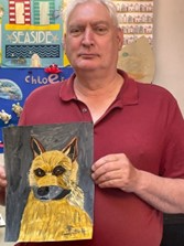 An older gentleman holds up his painting of a dog, completed in a Guideposts group.