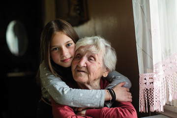 A smiling grandmother hugs are young granddaughter.