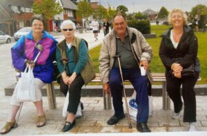 People including carers sitting on a bench.