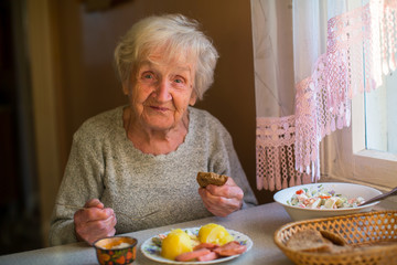 An elderly lady enjoying a meal smiles at the camera.