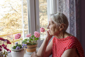 A lonely elderly lady looks out the window