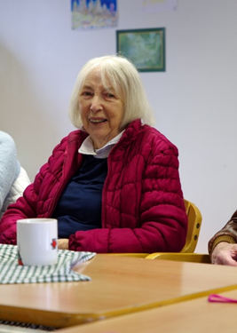 A smiling older lady with a cup of tea at a Guideposts Connect group