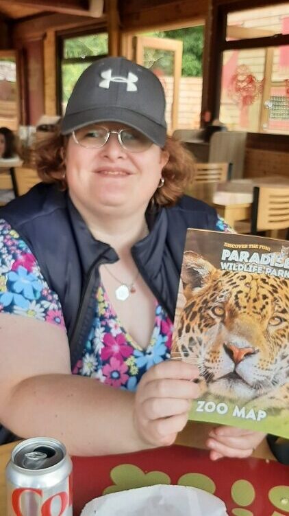 Sam smiling and holding a brochure for Paradise Park.