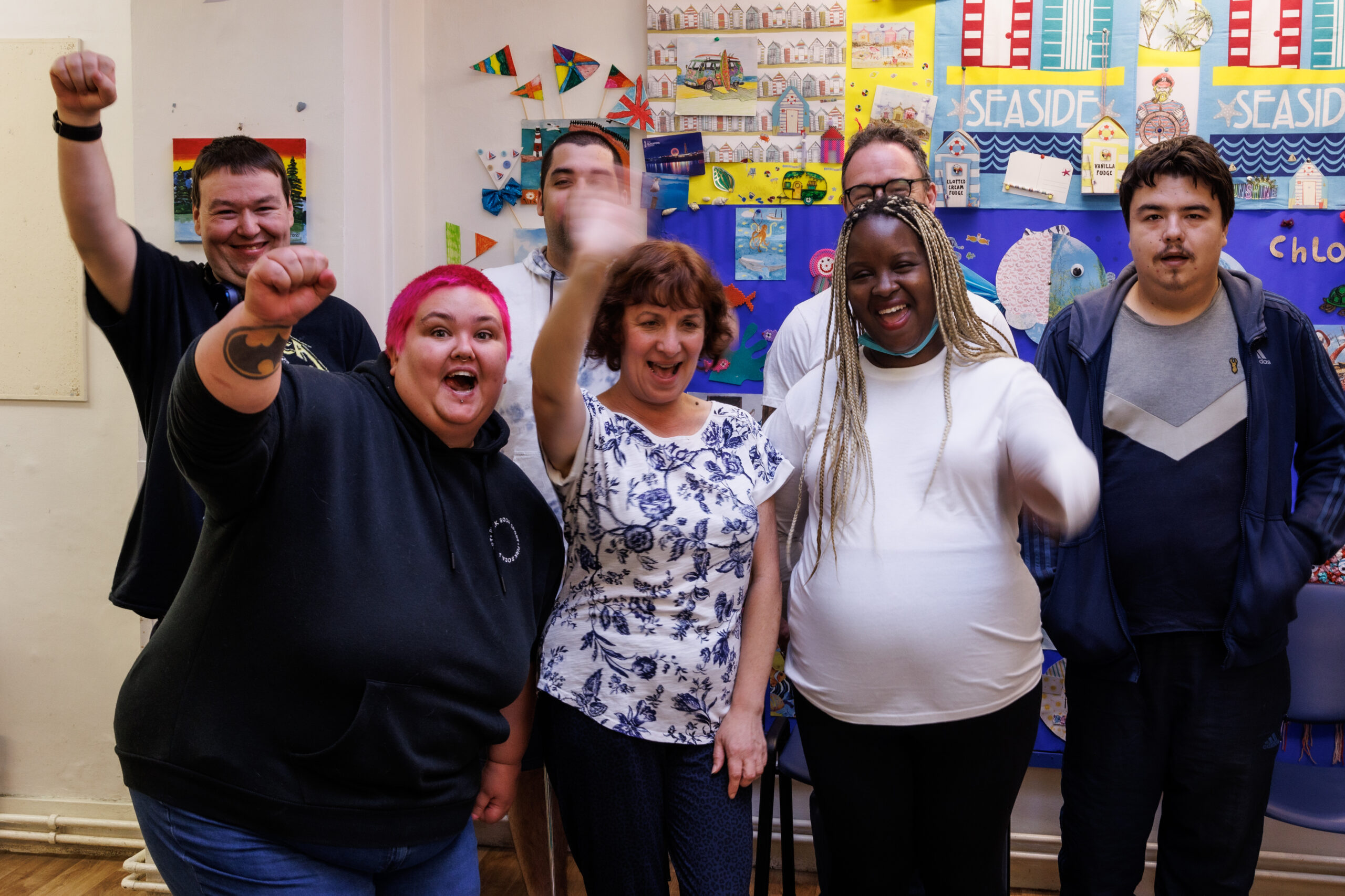 Group of people celebrating their service, with thumbs up and hands in the air.