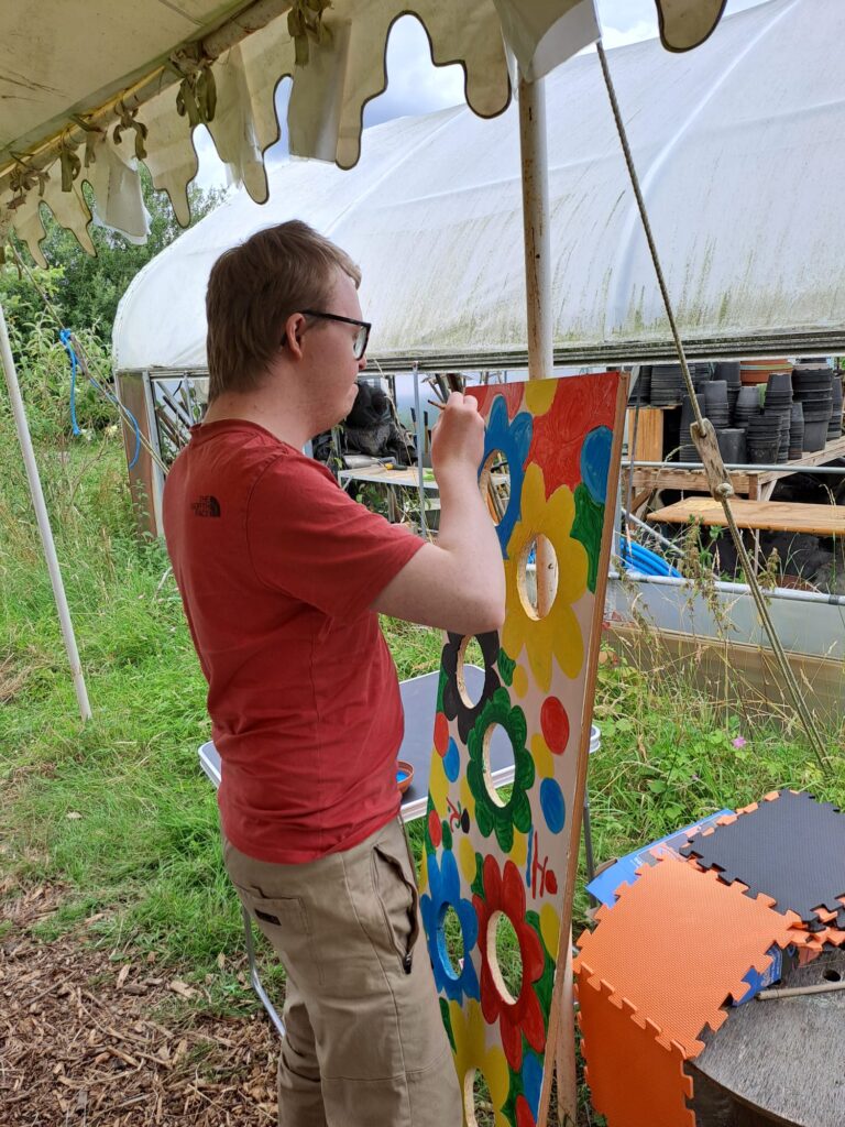 person paingint a board with holes in it bright colours