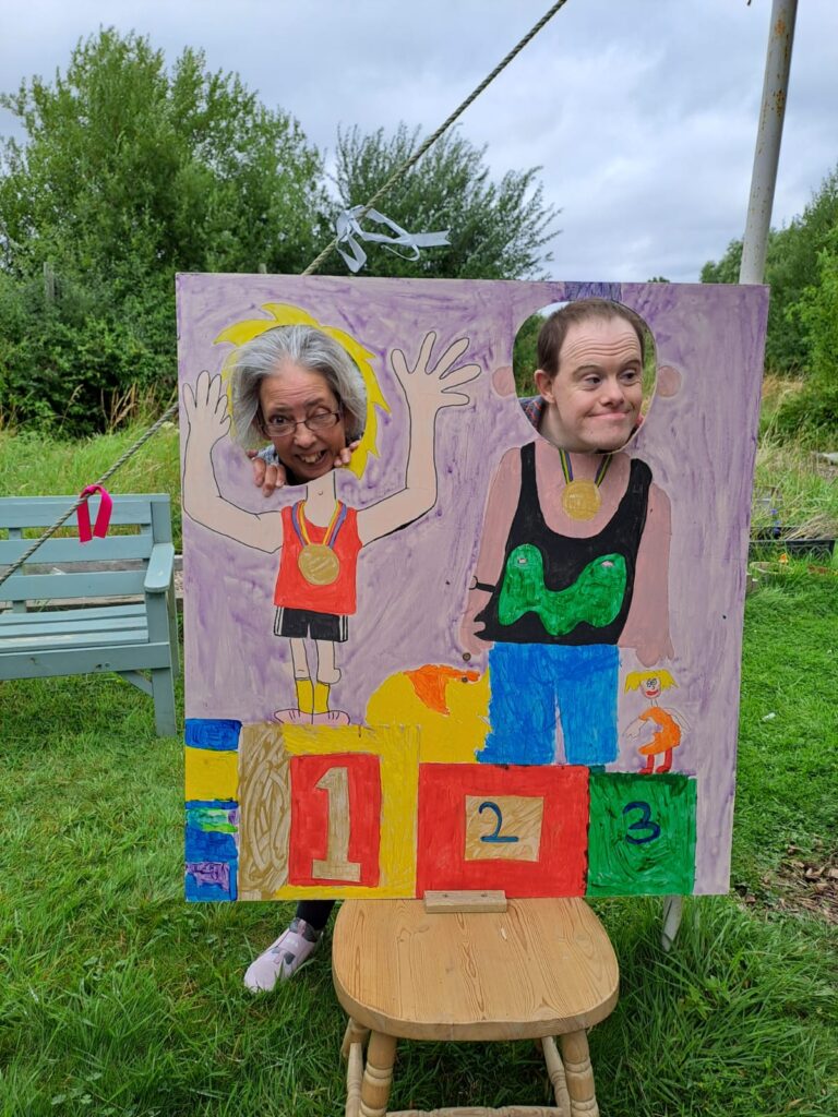 Two people with faces in brightly coloured seaside style face board