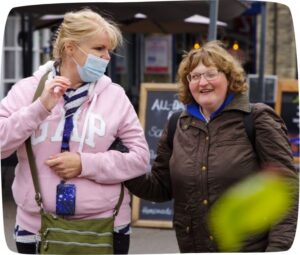 two women walking down a high street, chatting and smiling