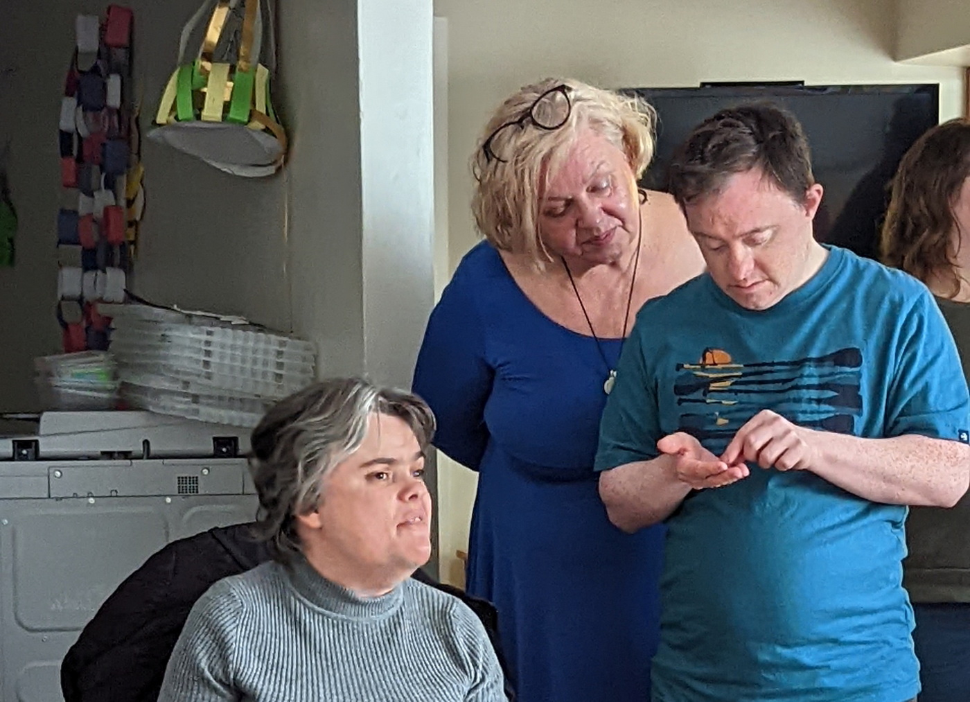 a group of 3 people. A young man is counting some money in his hand. A woman is overlooking to help him, and another woman is sitting next to them and taking interest.