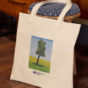 photo of a cotton tote bag lying against furniture. The bag has artwork printed on it of a textured tree, on plain natural colour fabric