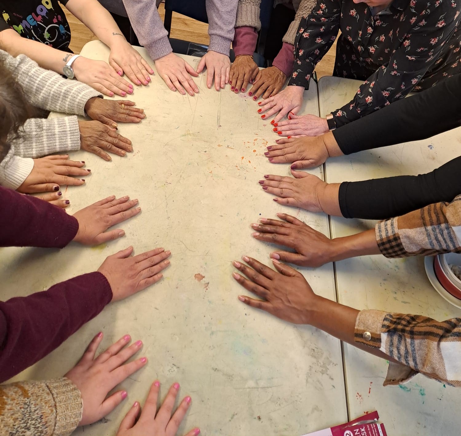 a table with many people's hands placed on it in a circle